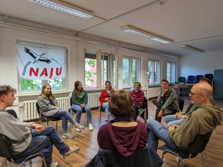 Eine kleine Menschengruppe sitzt in einem Stuhlkreis bei einem Workshop.